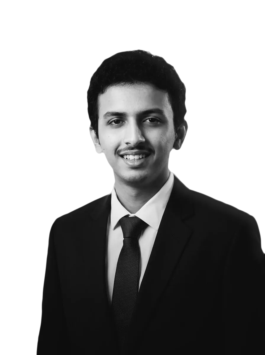 Shravan P Jois in a dark suit, white shirt and tie, smiling at the camera; black and white, on a green card.