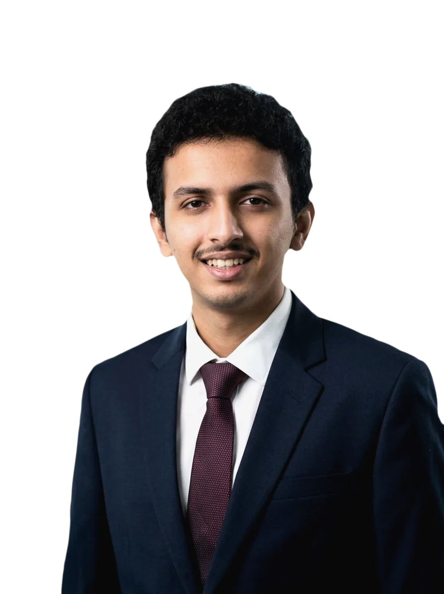 Shravan P Jois, smiling, in a navy suit, white shirt and burgundy tie; a colour photograph on a light studio backdrop.